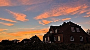 A brick house with a gabled roof and multiple windows, surrounded by vegetation. - Holiday apartment in Juist with swimming pool (Juist)