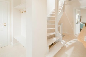 Ein heller Innenraum mit Treppe, Tür und Bank.