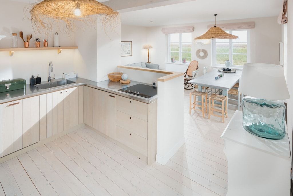 A modern kitchen with a central island, wooden cabinets, and a dining area with a table and chairs.