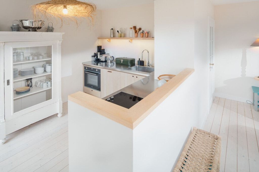 Una cocina moderna con armarios blancos, una isla central y una lámpara colgante.