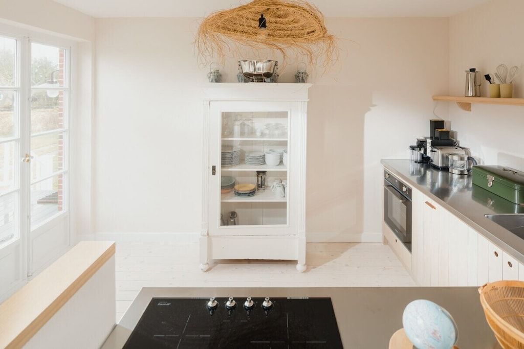 Una cocina con un armario blanco, una estufa y un colgador de luz.