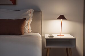 A neatly made bed with white and brown bedding, a bedside table with a lamp, and a small shelf. - Spacious apartment with balcony • Porto • 2 bedrooms (Porto)