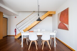 A modern interior with a dining table, chairs, a staircase, and a fire extinguisher. - Spacious apartment with balcony • Porto • 2 bedrooms (Porto)