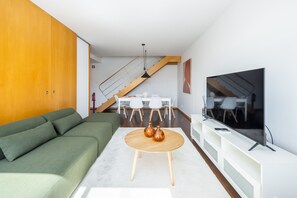 A modern living room with a green sofa, a round wooden coffee table, and a large flat-screen TV. - Spacious apartment with balcony • Porto • 2 bedrooms (Porto)