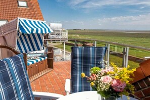 Eine Terrasse mit Sitzgelegenheit im Freien, Blick auf das Meer und eine Ziegelmauer.