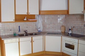 Una cucina con mobili bianchi, lavastoviglie, lavello e forno.