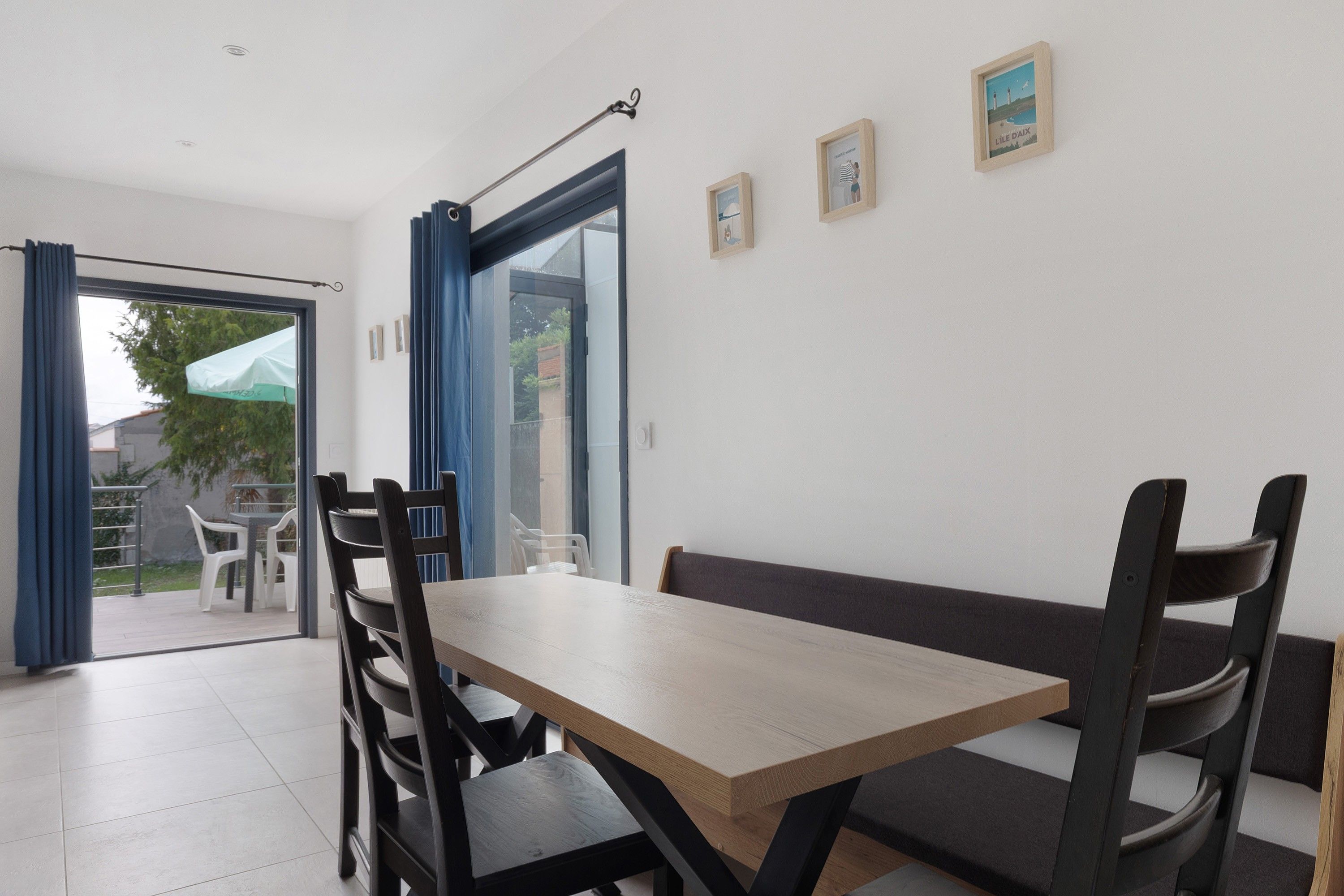 A dining area with a table and chairs, a bench, and a view through a glass door to an outdoor seating area.