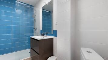 Une salle de bain moderne avec des carreaux bleus, un lavabo blanc et des toilettes.