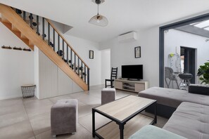 Una sala de estar moderna con una escalera, un televisor y un comedor.