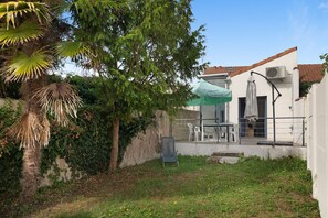 A building with a covered outdoor seating area, a palm tree, and a wall with ivy. - House with Garden South Beach Near Fouras Center (Fouras)