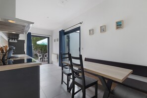 A modern kitchen with a dining area, a view of the outdoors, and a few framed pictures on the wall.