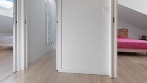 Una habitación con techo inclinado, una cama con edredón rosa y un radiador en la pared.
