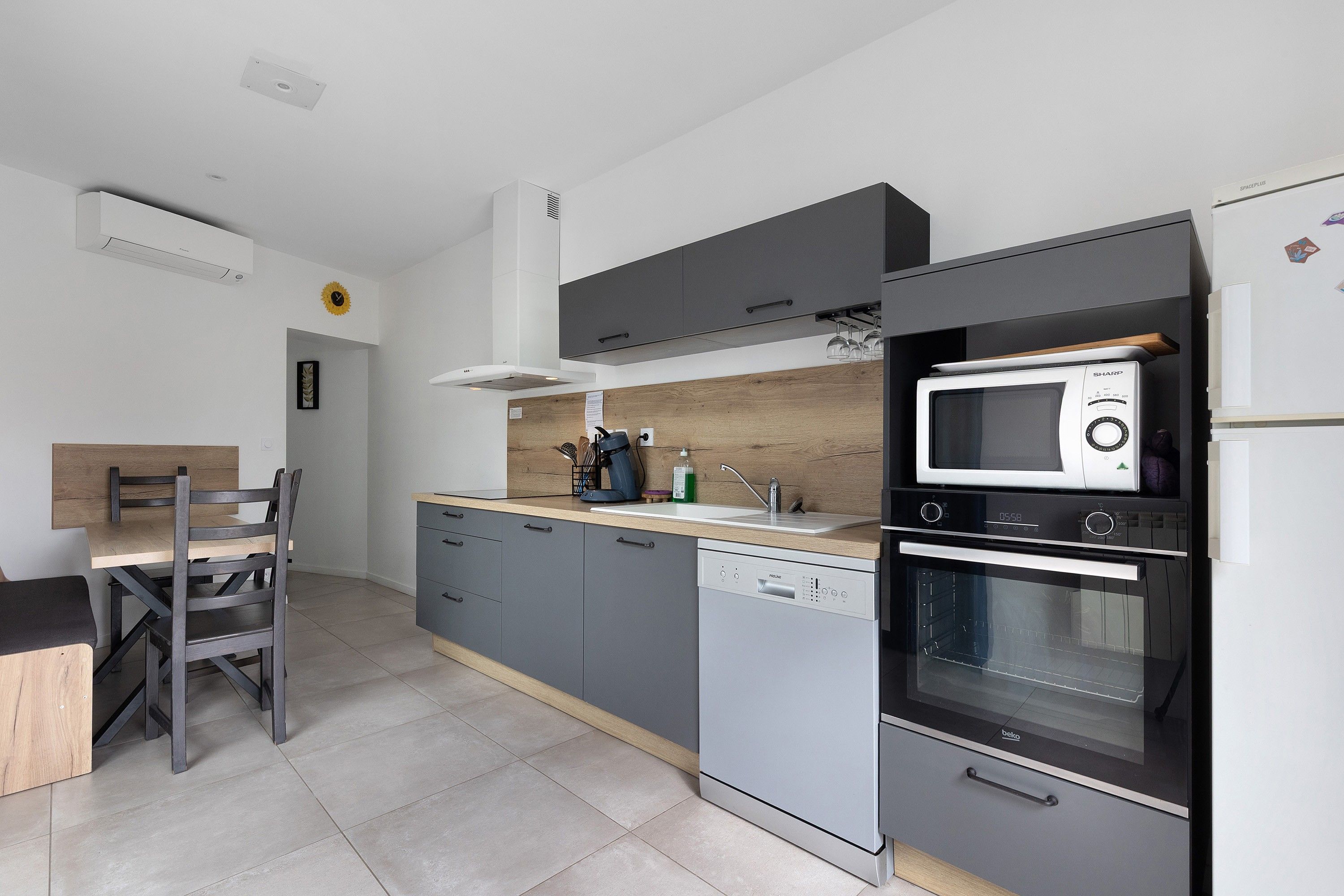 Une cuisine moderne avec des meubles gris, un four à micro-ondes encastré et un four traditionnel.