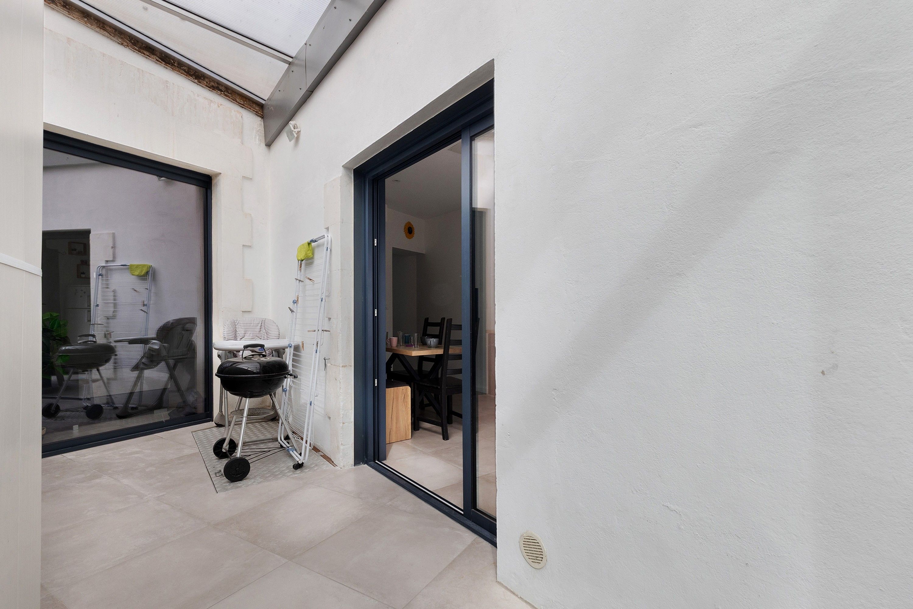 Un petit espace extérieur comprenant un barbecue, une chaise pliante et une table avec des chaises.