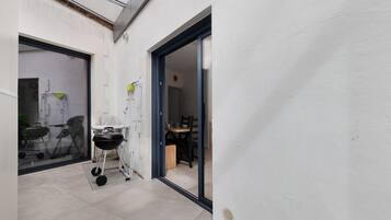 Un petit espace extérieur comprenant un barbecue, une chaise pliante et une table avec des chaises.