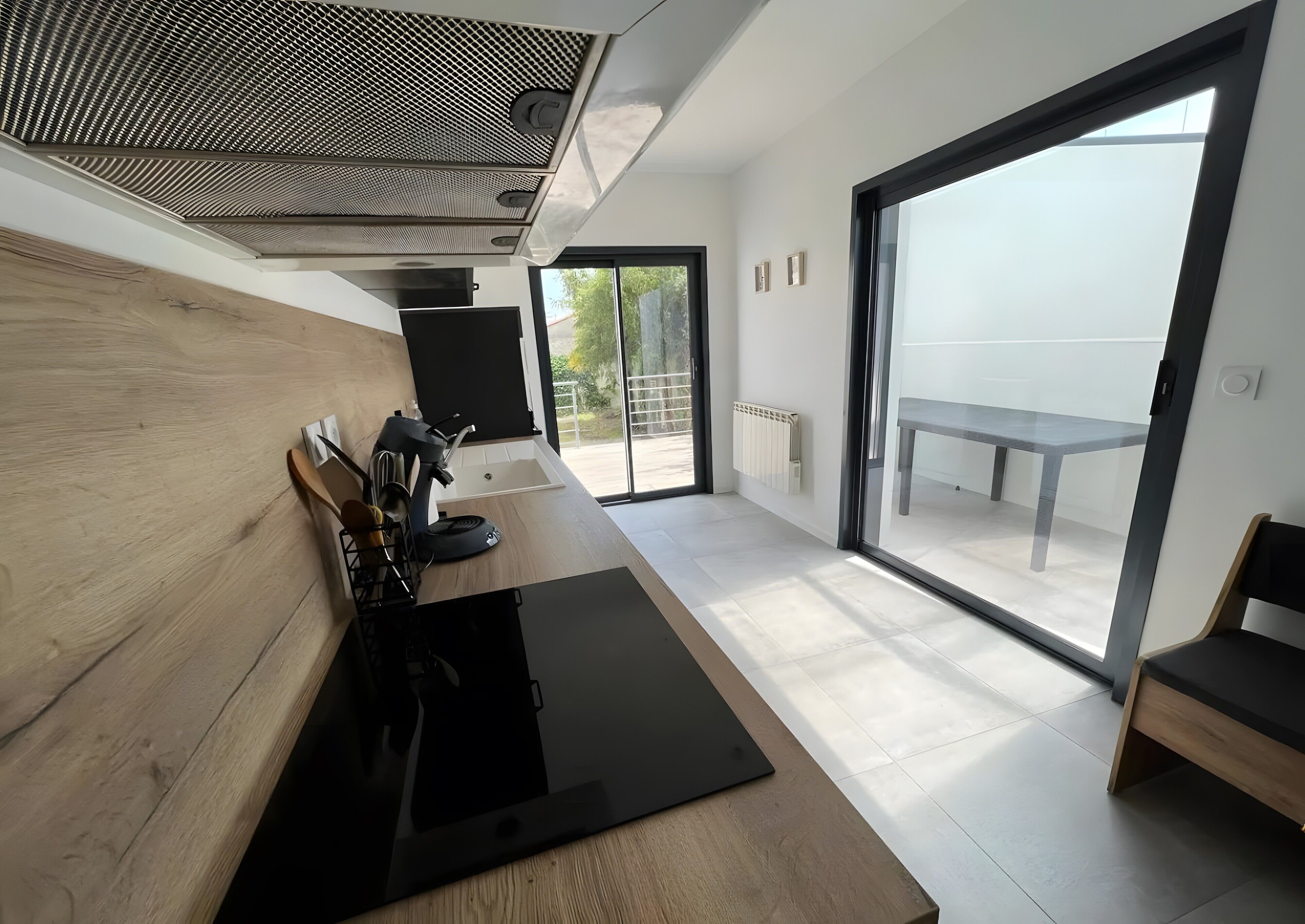 A modern kitchen with a black countertop, wooden cabinets, and a large window.