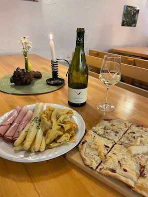 Uma mesa de jantar com uma garrafa de vinho, um copo, uma vela, um vaso com flores e pratos de comida.