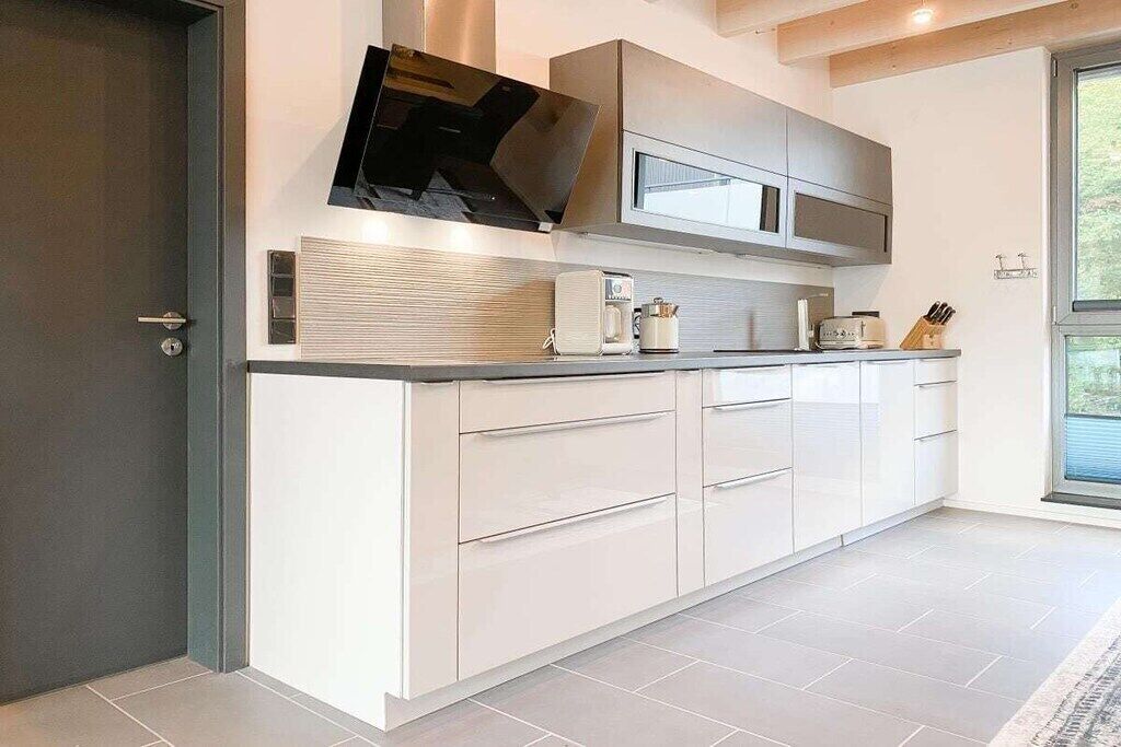 Een moderne keuken met een inbouwoven, magnetron en rvs-kasten.