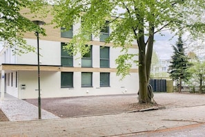Ein modernes Gebäude mit Flachdach, großen Fenstern und einem Baum davor.