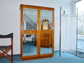 Une pièce avec une armoire en bois, une chaise, un radiateur et une fenêtre donnant sur un paysage agréable.