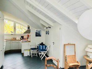 A compact kitchen with white cabinets, a dining area with a blue and white striped table, and a large window providing natural light. - in the Lake Park "heringsdorf" (Heringsdorf)