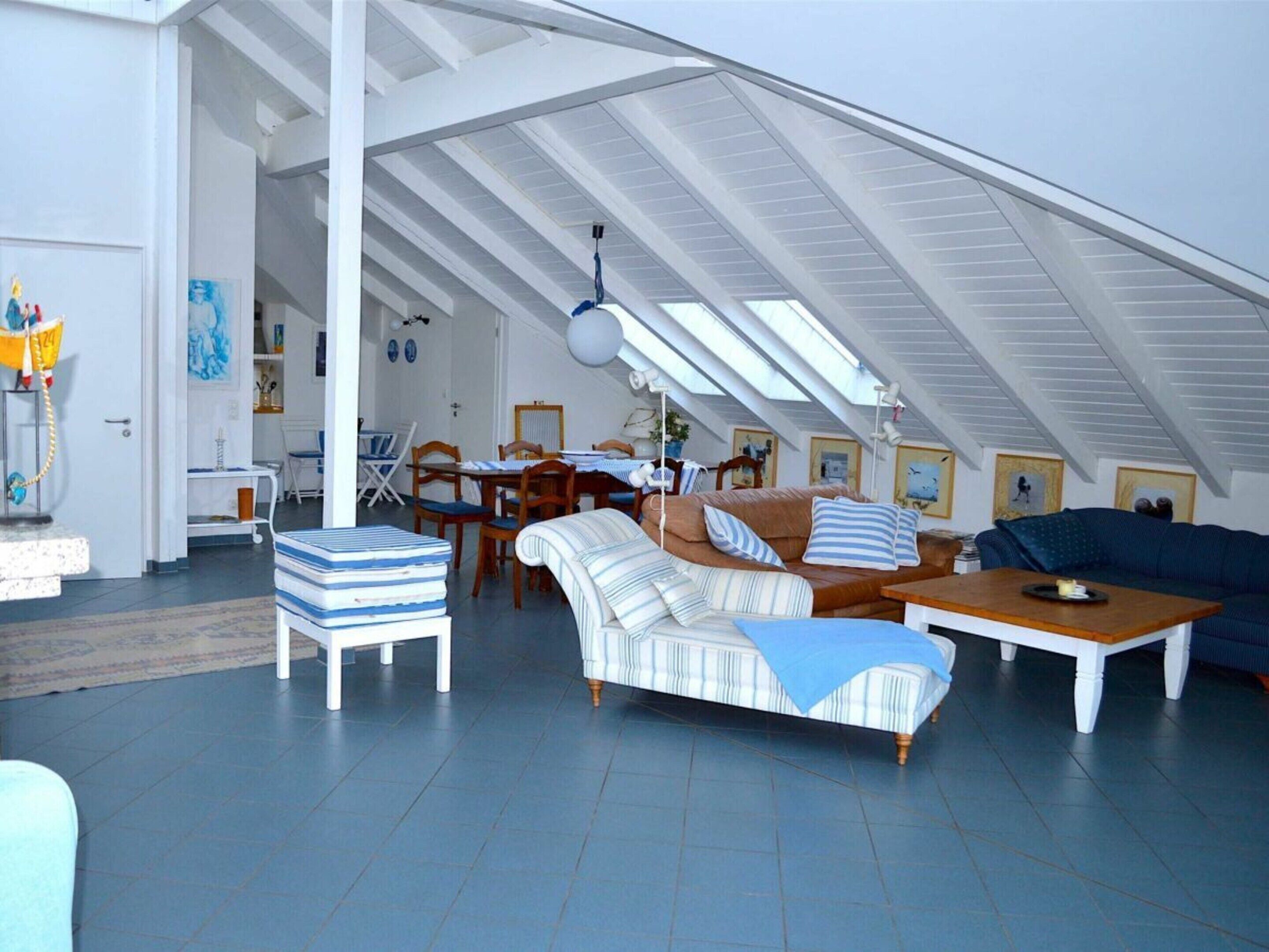 En rummelig loftetage med højt til loftet, et spiseområde og en opholdsstue møbleret med sofaer og et sofabord.