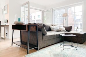 A modern living room with a grey sofa, a coffee table, and a side table. - Holiday apartment with 2 bedrooms (Timmendorfer Strand)