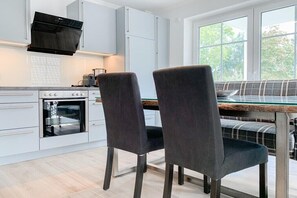 Eine moderne Küche mit weißen Schränken, einem eingebauten Backofen und einem Fenster mit Blick auf Grünflächen.