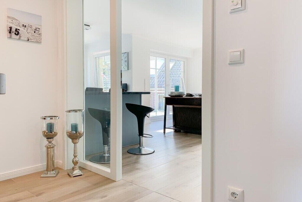 A modern interior with a glass partition, a dining area with a table and chairs, and two decorative candle stands.