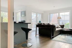 Ein modernes Wohnzimmer mit einer Couch, einer Bar und einem großen Fenster mit Blick ins Freie.