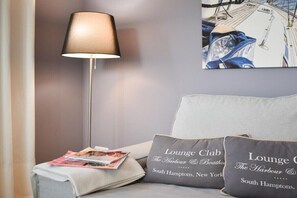 Une pièce comprenant un canapé, une lampe sur pied et deux coussins ornés de motifs textuels.
