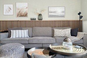 Ein modernes Wohnzimmer mit einem grauen Sofa, einem runden Couchtisch und einem Beistelltisch.