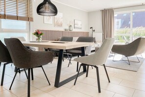 Ein stilvoller Essbereich mit einem Holztisch, grau gepolsterten Stühlen und einer schwarzen Pendelleuchte.