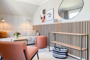 Ein modernes Wohnzimmer mit einer Couch, einem Hocker und einer Wandeinrichtung aus Holzlatten.