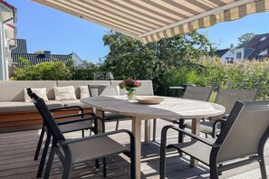 Une terrasse extérieure avec une table ronde, des chaises et un canapé.