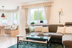 A living room with a glass coffee table, a sofa, and a lamp. - Holiday apartment with 1 bedroom (Timmendorfer Strand)