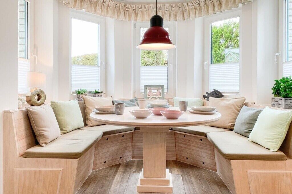 A corner seating area with a round table, cushioned benches, and a pendant light.