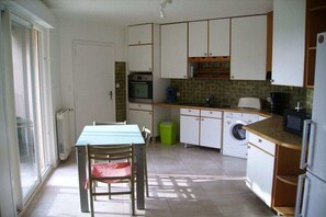 A compact kitchen with a dining table, chairs, a washing machine, and a microwave. - Holiday home in Vias with swimming pool (Vias)