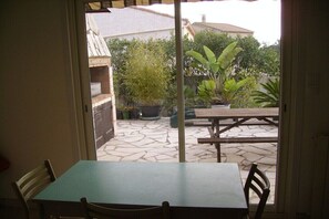 A patio area with a table and chairs, a stone floor, and potted plants. - Holiday home in Vias with swimming pool (Vias)