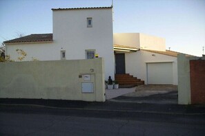 A two-story building with a garage, a small front porch, and a white exterior. - Holiday home in Vias with swimming pool (Vias)