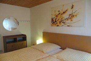 A bedroom with a bed, a dresser, a mirror, and a wall-mounted artwork. - Holiday home in Bürberg with swimming pool (Bürberg)