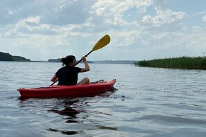 Una persona en kayak sobre aguas tranquilas, bajo un cielo despejado.
