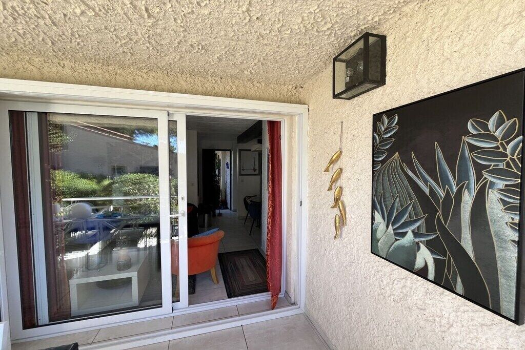 A room with a sliding glass door leading to an outdoor area, a red curtain, and a framed artwork on the wall.