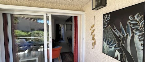 A room with a sliding glass door leading to an outdoor area, a red curtain, and a framed artwork on the wall.