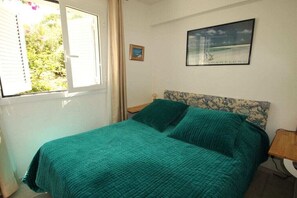A bedroom with a bed, a window, a framed picture on the wall, and a nightstand. - Holiday apartment in Lumio with swimming pool (Lumio)