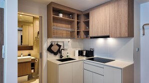 A compact kitchen with a sink, stove, and wooden cabinets. - 2BR family suite near Boat Lagoon (BangTao)