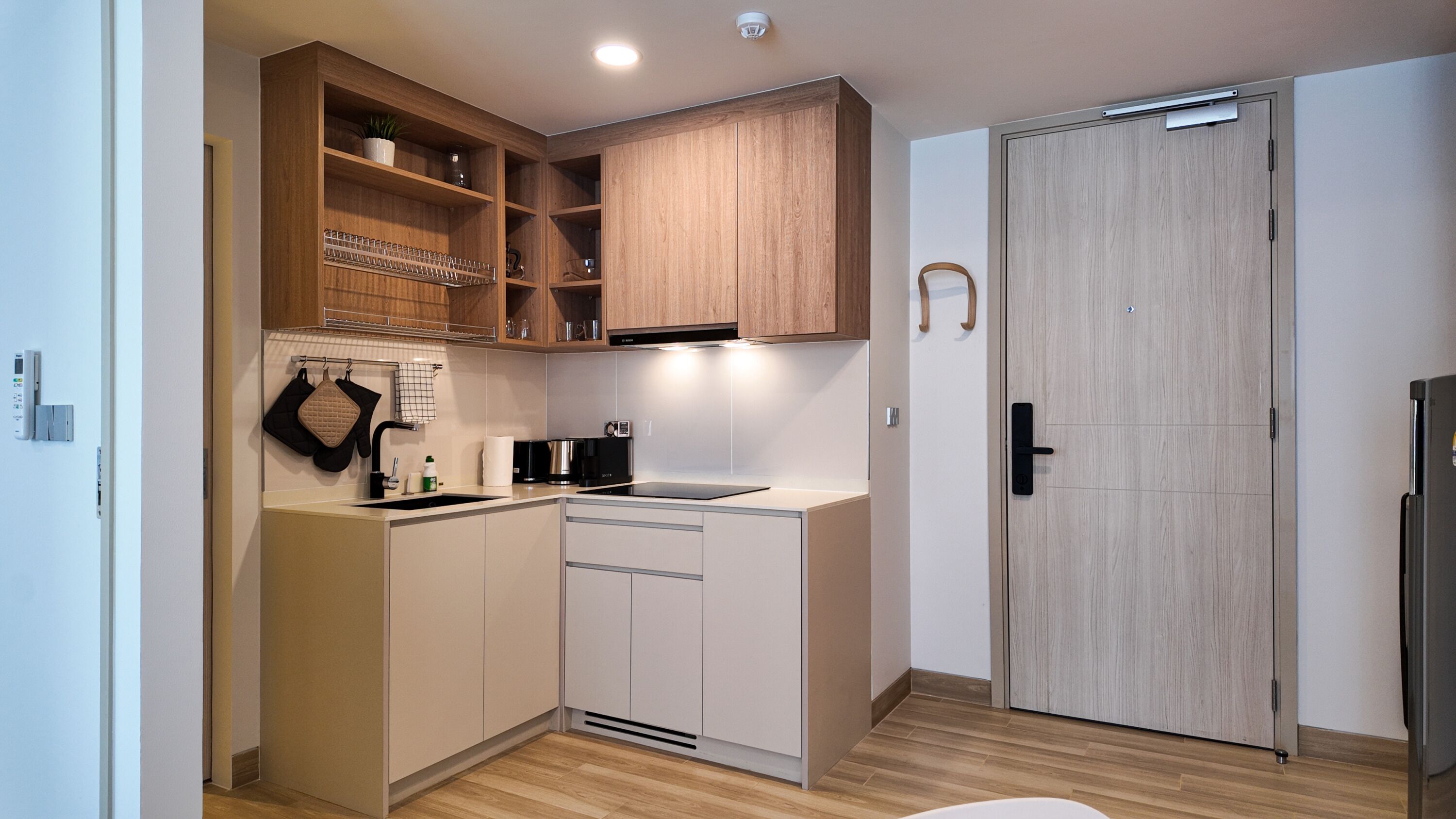 Eine kleine Küche mit Holzschränken, einer schwarzen Induktionskochplatte und einem eingebauten Backofen.