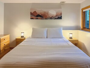 Ein Schlafzimmer mit einem Bett, zwei Nachttischen, einer Holzkommode und einem Bild an der Wand.