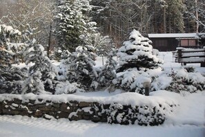 A snow-covered landscape with a stone wall and a wooden cabin. - Holiday home with 1 bedroom (Kurort Oybin)