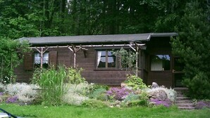 A rustic cabin with a porch, surrounded by a well-maintained garden with various plants and flowers. - Holiday home with 1 bedroom (Kurort Oybin)